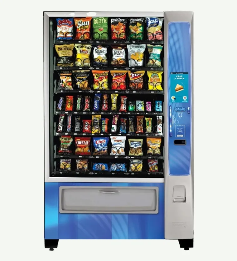 Crane Merchant Media 2 glass-front snack vending machine with a nine-inch color touchscreen, stocked across seven trays with chips, candy bars, cookies and baked snacks